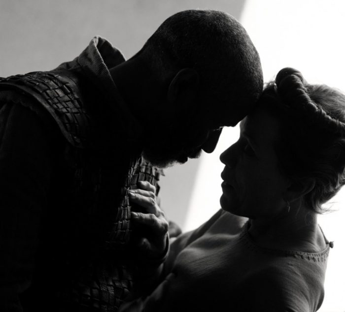 Lord Macbeth and Lady Macbeth touch foreheads in an embrace.