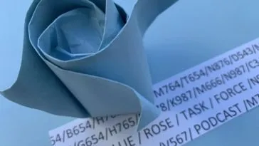 A blue oragami rose on a sheet of random code that contains the words "Blue Rose Task Force"e