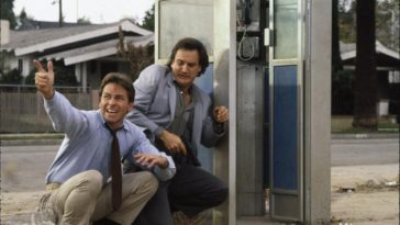 John Ritter providing "cover" to James Belushi outside of a phone booth.
