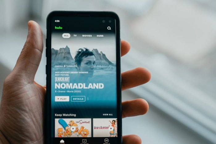A person is holding a cellphone showing the Hulu app