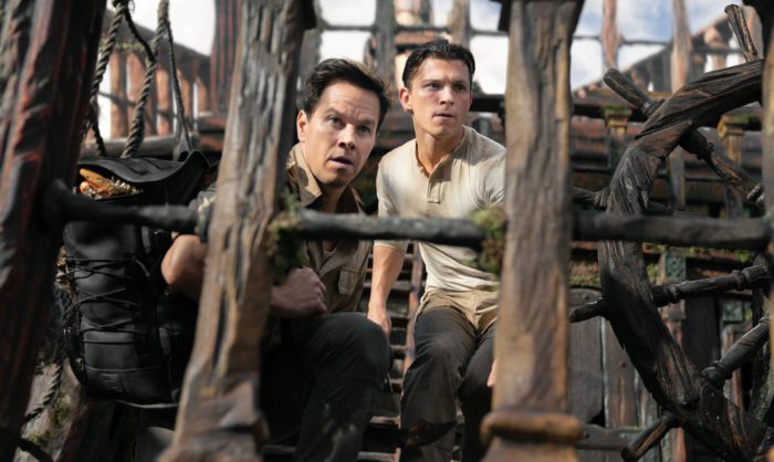 Two men look look through a ship ladder at chasing danger.