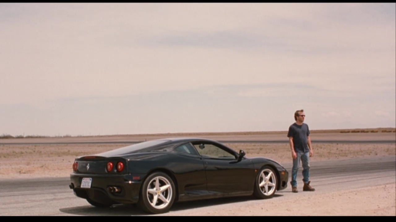 Image from Somewhere: Johnny Marco (Stephen Dorff) stands in front of Ferrari on a desert racetrack.