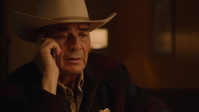 Robert Forster as Frank Truman, holding a phone in his right hand