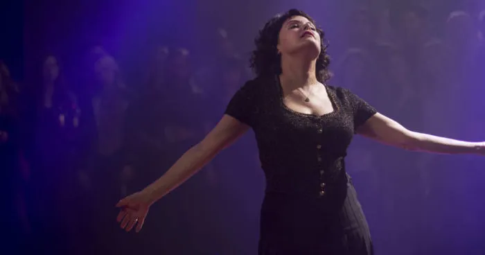 Audrey Horne dancing in front of an out of focus crowd, her arms outstretched, her eyes closed, and an almost blissful expression on her face