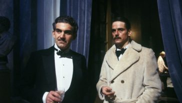Rex Mottram (Charles Keating) and Charles Ryder (Jeremy Irons) dressed for dinner, and frowning, as they discuss the quirky and unfathomable Marchmains. From the 1981 Granada (ITV) production of Brideshead Revisited.
