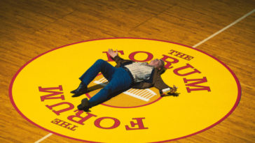 Jerry Buss (John C. Reilly) lays in the center of a basketball court in Winning Time S1E1