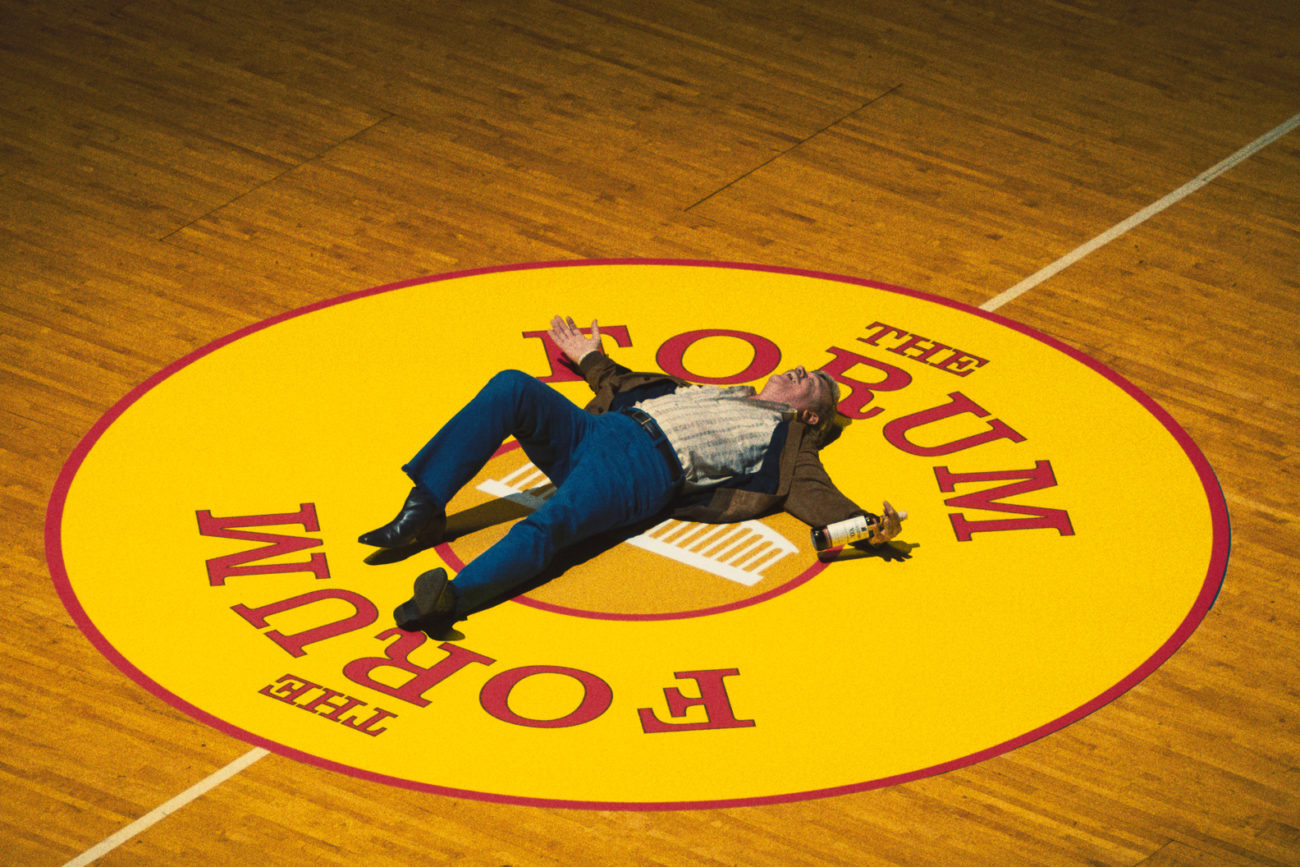 Jerry Buss (John C. Reilly) lays in the center of a basketball court in Winning Time S1E1