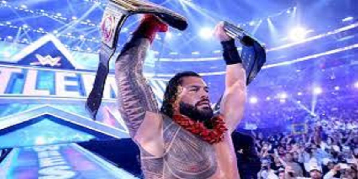 Roman Reigns holds up his two title belts