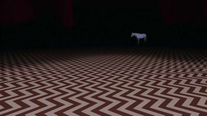 The white horse appears in the Red Room against a backdrop of darkness.