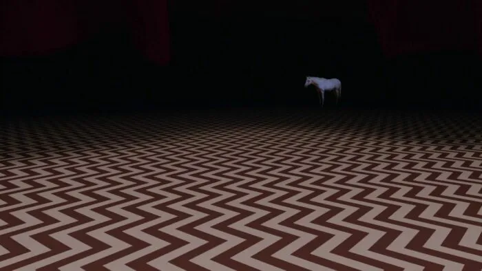 The white horse appears in the Red Room against a backdrop of darkness.