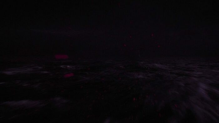 Red flecks of light scattering across the purple ocean under the Fireman's palace.