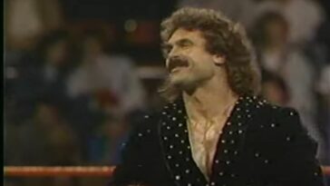 Rick Rude stands in the ring