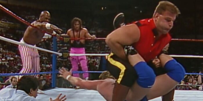 The Mountie applies a Boston crab as Roddy Piper reaches out for a tag with a hand-outstretched Virgil.