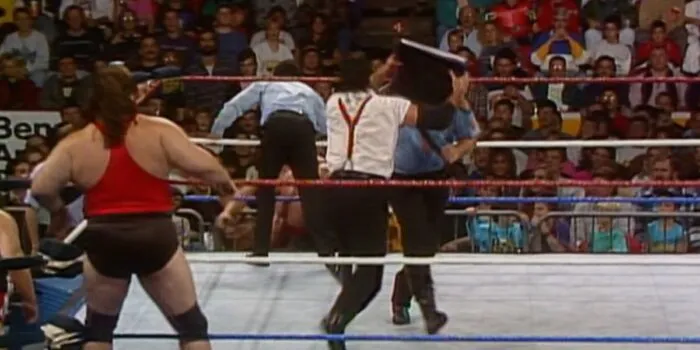 I.R.S. smashes Boss Man in the face with his briefcase behind the referee's back.