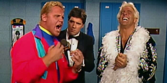 A passionate Mr Perfect cuts a promo as Ric Flair beams with joy, his hands clasped.