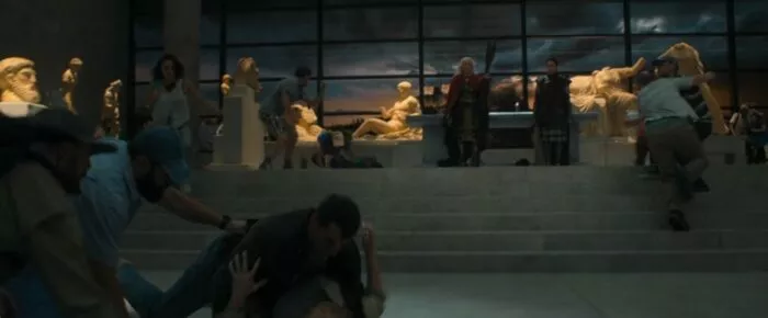 The Daughters of Atlas standing in front of groups of people attacking each other, they watch in glee as the chaos they created unfolds