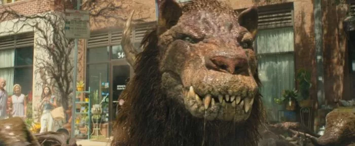 A manticore stands in the middle of the street with a ferocious look on its face, drool drips from its yellowed teeth. People on the street look on in shock and horror.