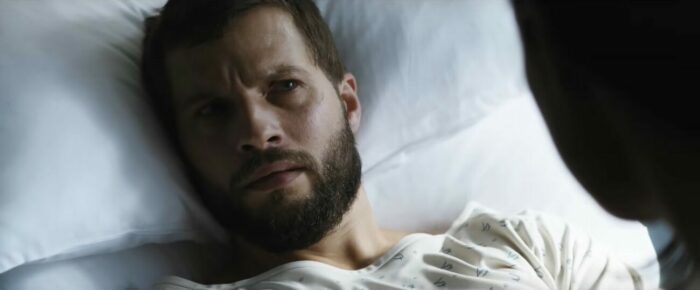Grey in a hospital bed looking incredulous