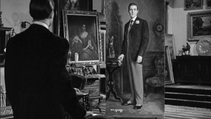 A man stands in the foreground, with his back towards the camera. Between him, and the man in the background, a lavish painting faces out.