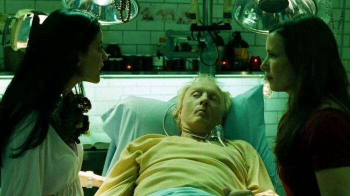 Lynn and Amanda on either side of Jigsaw's bed in Saw III