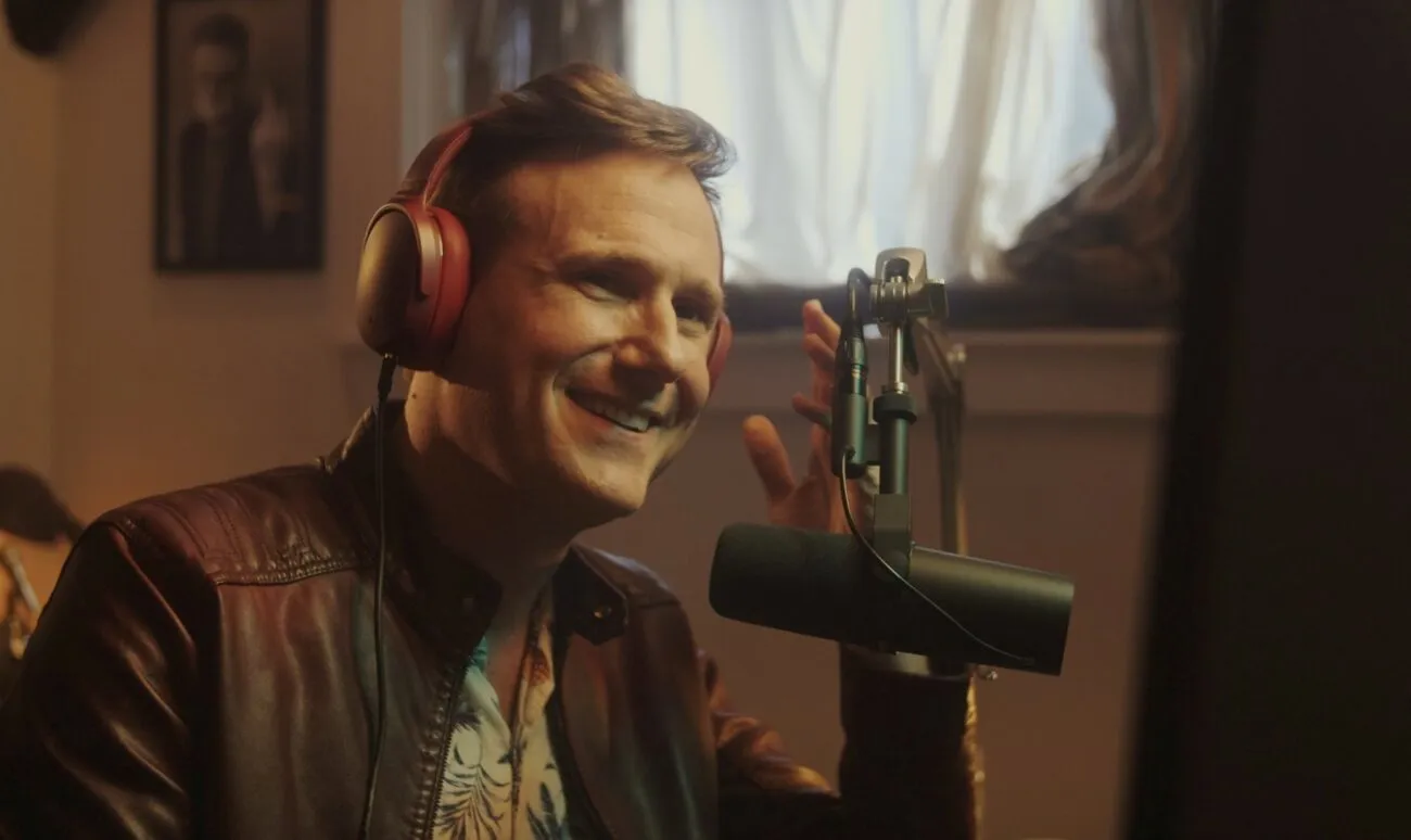 A man smiling and talking into a mic