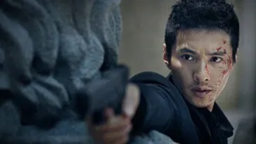 The Man From Nowhere looks out from behind cover, holding a gun.