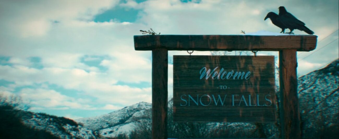 A large wooden sign with two crows sitting atop it says "Welcome to Snow Falls."