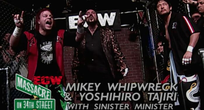 Mikey Whipwreck gives the devil horns with his fingers as Minister and Tajiri look forward sternly.