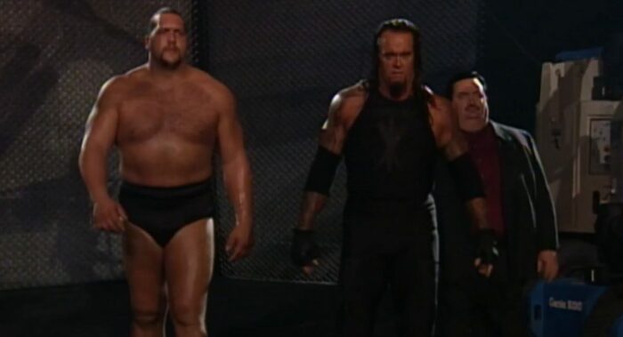 A deadpan Undertaker, Big Show, and Paul Bearer walk to the ring in the dark.