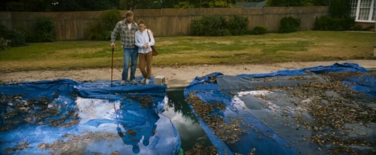 Two people standing outside an old pool