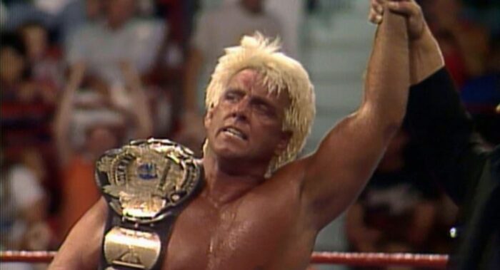 Ric Flair has his arm raised in victory, the WWF World Heavyweight championship over his shoulder.