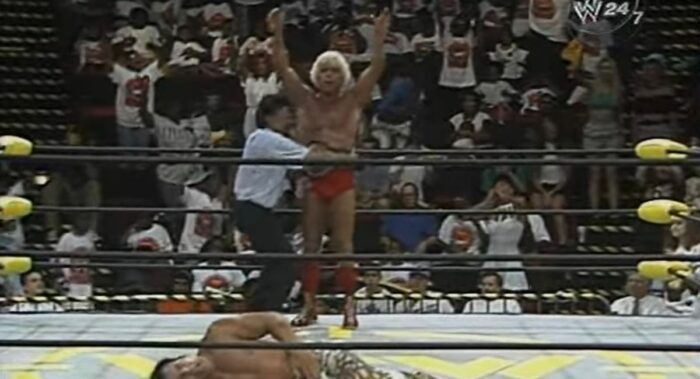 The ref straps the WCW World Title belt around Ric Flair's waist as Ricky Steamboat lies on the mat in pain