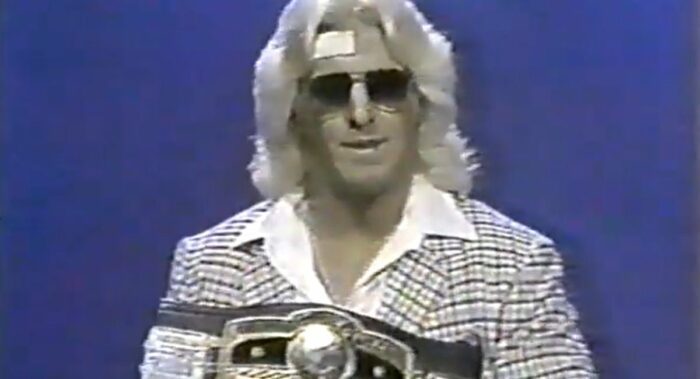 A sharp-looking Ric Flair hold the Ten Pounds of Gold.