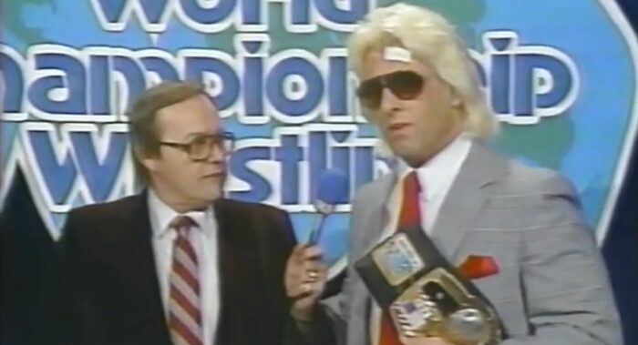 A suited Ric Flair talks to Gordon Solie on the set of GCW'S World Championship Wrestling