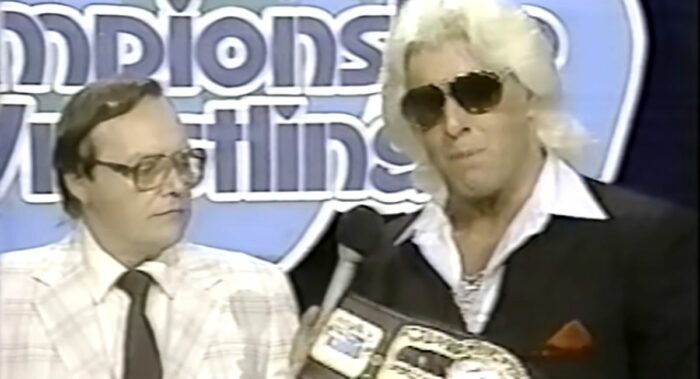 Gordon Solie looks appreciatively at the Ten Pounds of Gold while Ric Flair address the camera.