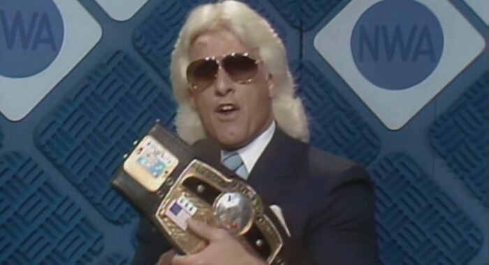 Ric Flair holds up the NWA Heavyweight belt for the camera's inspection