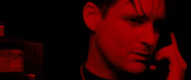 Fred looks upset as he is on the phone, with a red filter over him