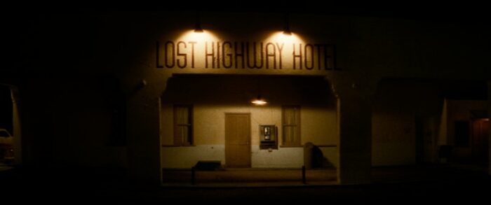 The Lost Highway Hotel, lit by two dim lights, mostly shrouded in darkness