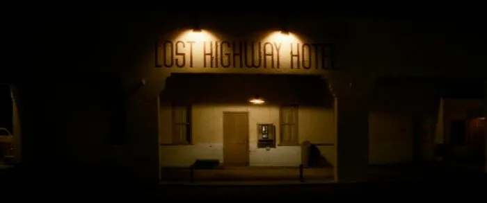 The Lost Highway Hotel, lit by two dim lights, mostly shrouded in darkness