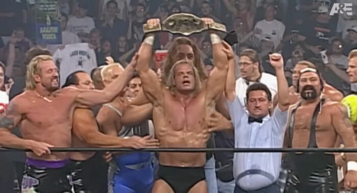Lex Luger holds aloft the WCW World Heavyweight Championship belt, as many of the WCW locker room celebrate in the ring with him