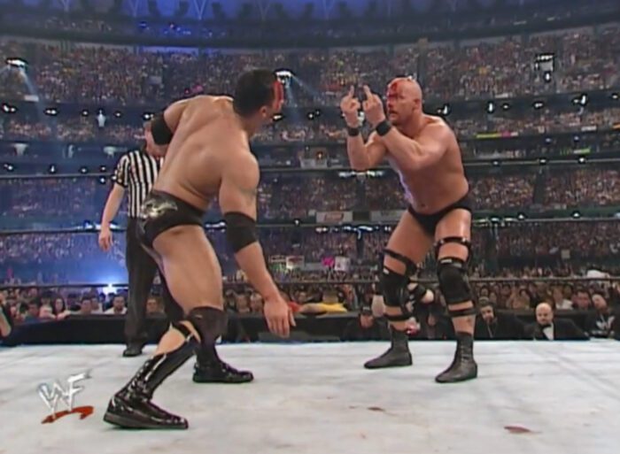 A bloody Steve Austin gives the double bird to a bloody Rock at WrestleMania X7
