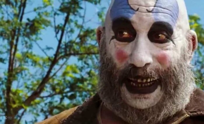 Captain Spaulding looks on in glee as he terrorizes a woman and her child