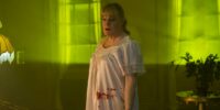 Nina is seen in the yellow light while wearing a bloody nightgown