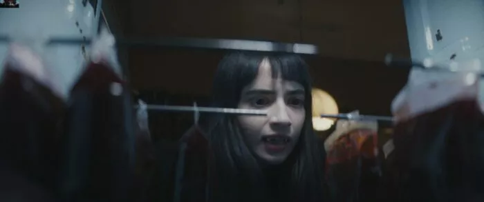 A girl with fangs looks at her stock of blood packs