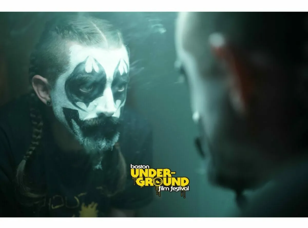 Trey looks at his black and white painted face in the mirror