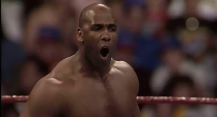 Virgil shouts at someone unseen at ringside
