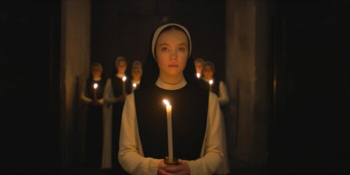 A nun holding a candle in front of other nuns with candles