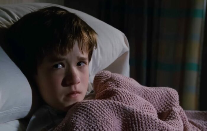A boy in a bed looking scared