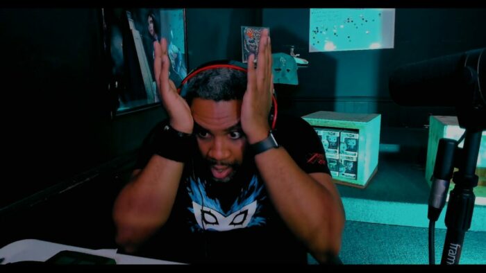A man looks exasperated sitting at a desk and holding his temples in LIVESCREAMERS