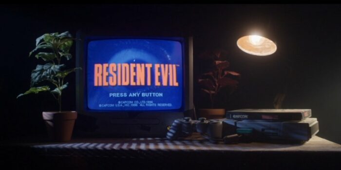 A TV screen displays a start menu for Resident evil next to a video game console, plant, and desk lamp